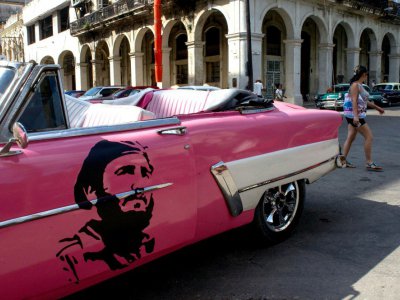 Un portrait de Fidel Castro jeune sur la portière d'une vieille voiture américaine dans une rue de La Havane, le 24 novembre 2017 à Cuba - YAMIL LAGE [AFP]