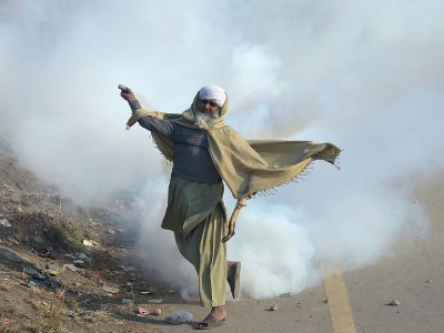Un manifestant islamiste pakistanais renvoie une grenade lacrymogène sur les forces de l'ordre samedi 25 novembre 2017 à Islamabad - AAMIR QURESHI [AFP]
