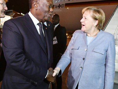 Le président ivoirien Alassane Ouattara accueille la Chancelière  allemande Angela Merkel à son arrivée à l'aéroport d'Abidjan, le 28 novembre 2018 - ISSOUF SANOGO [AFP]