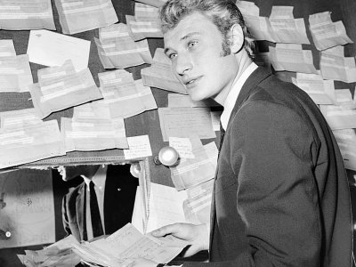 Johnny Hallyday le 25 novembre 1965 dans sa loge tapissée de télégrammes d'encouragement, avant un concert à l'Olympia - [AFP/Archives]