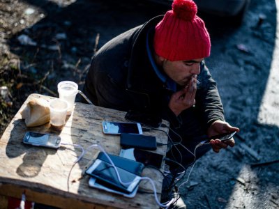 Un migrant recharge son téléphone portable à Sid en Serbie, près de la frontière avec la Croatie, le 7 décembre 2017 - Andrej ISAKOVIC [AFP]