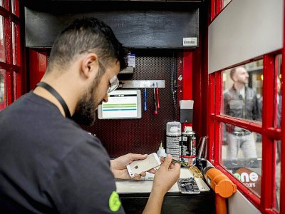 Fouad Choaibi répare des smartphones dans une ancienne cabine téléphonique à Londres, le 20 octobre 2017 - Tolga Akmen [AFP]