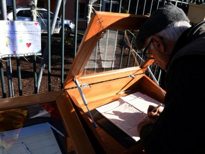 Un homme signe le registre de condoléances de la mairie de Saint-Féliu-d'Avall le 16 décembre 2017 - PASCAL PAVANI [AFP]
