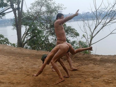 Des adeptes du naturisme font des exercices d'échauffement sur les rives du fleuve Rouge, le 11 décembre 2017 à Hanoï, au Vietnam - HOANG DINH NAM [AFP]