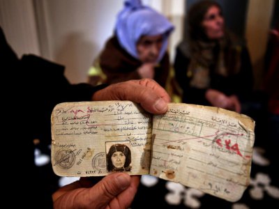 Un membre de sa famille montre les papiers de Laila Saleh (en arrière-plan) , à Athènes, le 15 décembre 2017 - ARIS MESSINIS [AFP]