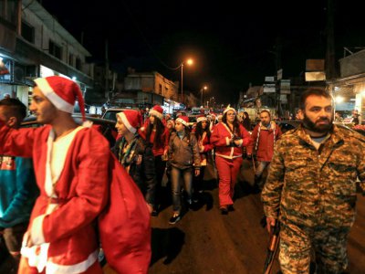 Des Syriens habillés en Père Noël déambulent dans les rues de Damas escortés par des militaires le 24 décembre 2017 - LOUAI BESHARA [AFP]