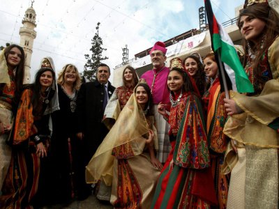 L'archevêque Pierbattista Pizzaballa avec des Palestiniennes en habit traditionnel pour fêter Noël sur la place de la Mangeoire devant l'église de la Nativité à Bethléem, le 24 décembre 2017 - Musa AL SHAER [AFP]