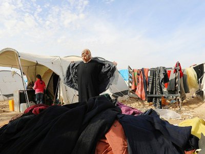 Une femme déplacée par les combats en Syrie tente de trouver un anorak dans une pile de vêtements usagés au camp d'Aïn Issa, le 18 décembre 2017 - Delil souleiman [AFP]