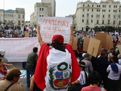 Un manifestant brandit une pancarte qualifiant Fujimori d'"assassin et dictateur" pendant une manifestation contre la grâce accordée à l'ancien président, le 25 décembre à Lima - Juan Vita [AFP]