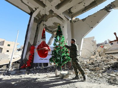 Un membre des Forces démocratiques syriennes devant un sapin de Noël dans ce qui reste de l'église des Martyrs à Raqa le 26 décembre 2017 - Delil souleiman [AFP]