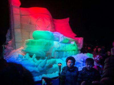 Des enfants nord-coréens prennent la pause devant une sculpture en glace représentant un lanceur de missile, le 31 décembre 2017 à Pyongyang - KIM Won-Jin [AFP]