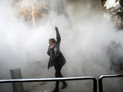 Une Iranienne lève le poing dans la fumée des gaz lacrymogènes lors d'une manifestation à Téhéran, le 30 décembre 2017 - STR [AFP]