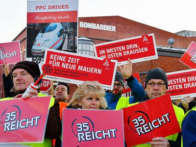 Des salariés de la métallurgie à l'usine Bombardier manifestent à Hennigsdorf près de Berlin et brandissent des panneaux de IG Metall, le 8 janvier 2018 - Bernd Settnik [dpa/AFP]