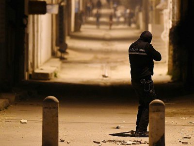 Un membre des forces de sécurité tunisiennes fait face à des protestataires dans le quartier d'Ettadhamen, en banlieue de Tunis, le 10 janvier 2018 au soir - FETHI BELAID [AFP]