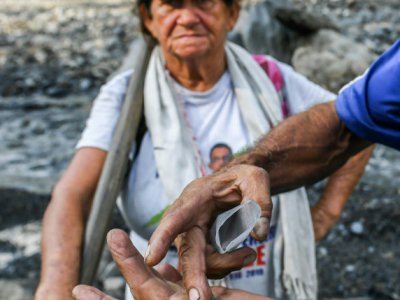 Blanca Biutrago, chercheuse d'émeraude, à côté d'un autre chercheur qui montre des émeraudes trouvées dans le torrent de Las Animas, le 19 décembre 2017 à Muzo, en Colombie - Luis ACOSTA [AFP]