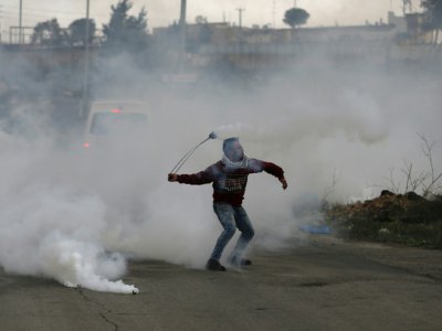 Un Palestinien lance une grenade lacrymogène sur des forces israéliennes près de la colonie israélienne de Beit El, en Cisjordanie occupée, le 23 janvier 2018 - ABBAS MOMANI [AFP]