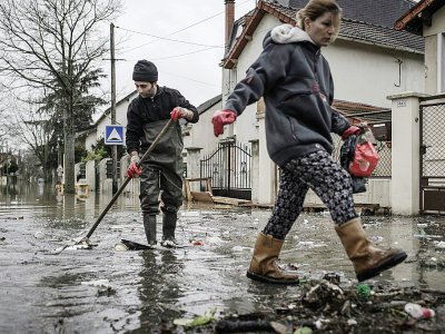 Des habitants nettoient les débris dans une rue inondée de Villeneuve-Saint-Georges le 25 janvier 2018 - Philippe LOPEZ [AFP]