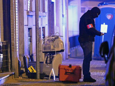Un enquêteur est à la recherche d'indices, le 19 mars 2016 à Molenbeek à l'extérieur du bâtiment où a été arrêté la veille Salah Abdeslam - DIRK WAEM [Belga/AFP/Archives]
