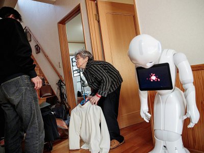 La Japonaise Kimiko Nishimoto chez elle avec son fils Kazutami et son robot androïd Pepper (d), le 16 janvier 2017 à Kumamoto - Behrouz MEHRI, Behrouz MEHRI [AFP]
