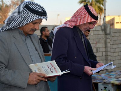 Des Irakiens feuillettent des livres dans une rue de Mossoul (nord), six mois après sa libération des jihadistes, le 12 janvier 2018 - Ahmad MUWAFAQ [AFP]