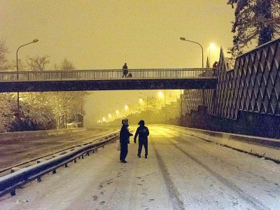 Des gens marchent sur la route principale N118 déserte et enneigée près de Vélizy-Villacoublay tôt le 7 février 2018, après sa fermeture suite à de fortes chutes de neige - Samuel Boivin [AFP]