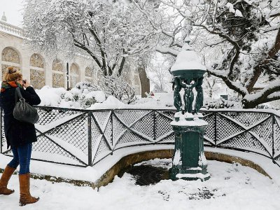 Une femme prend en photo une fontaine Wallace à Montmartre, le 7 février 2018 - PATRICK KOVARIK [AFP]