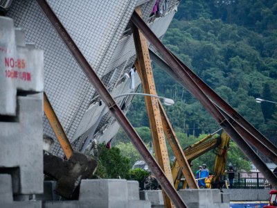 La tour Yun Tsui, gravement endommagée après le séisme et penchant à un angle précaire, est soutenue par des poutres métalliques, le 8 février 2018  à Hualien à Taïwan - Anthony WALLACE [AFP]