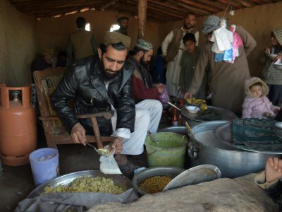 Des réfugiés afghans servent de la nourriture à d'autres réfugiés dans un camp près d'Islamabad, le 19 janvier 2018 - AAMIR QURESHI [AFP]