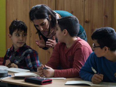 En classe, l'assistante Hend Al Khabbaz aide de jeunes Syriens, réfugiés comme elle, dans leur apprentissage. Parfois, elle leur parle explique en arabe des notions qu'ils n'ont pas comprises en allemand. A Fürstenwalde, le 19 janvier 2018 - John MACDOUGALL [AFP]