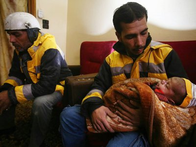 Samir Salim et ses trois frères, tous secouristes des Casques blancs syriens dans la Ghouta orientale, se tiennent aux côtés d'un de leurs collègues tenant un bébé, à Madira, le 12 février 2018 - ABDULMONAM EASSA [AFP]