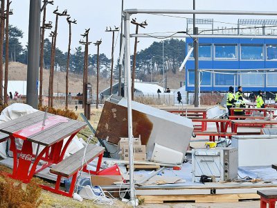 Des policiers près des stands de nourriture qui se sont envolés à cause des vents violents, à l'extérieur de la patinoire Arena de Gangneung, le 14 février 2018 - Mladen ANTONOV [AFP]