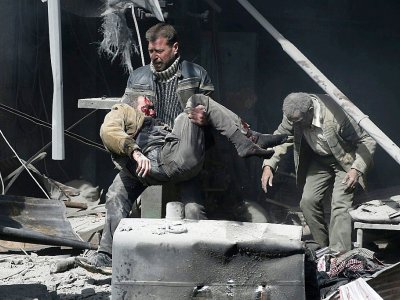 Un homme au secours d'un blessé après les bombardements du régime syrien contre la ville rebelle de Hammouriyé, le 19 février 2018 - ABDULMONAM EASSA [AFP]
