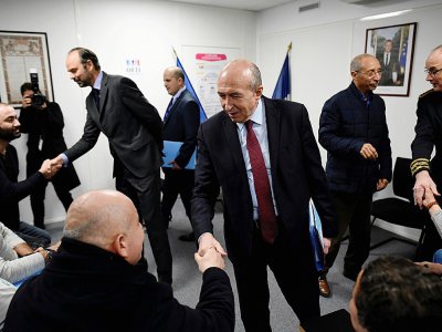 Le ministre de l'Intérieur Gerard Collomb (au centre) serre la main à un réfugié qui a signé un contrat d'intégration républicaine le 19 février 2018 à Lyon - JEAN-PHILIPPE KSIAZEK [AFP/Archives]