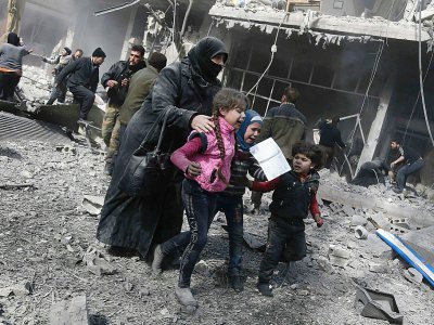 Une femme et des enfants cherchent un abri après des bombardements sur la ville de Hamouria, dans l'enclave rebelle de la Ghouta orientale, près de Damas le 19 février 2018 - ABDULMONAM EASSA [AFP]