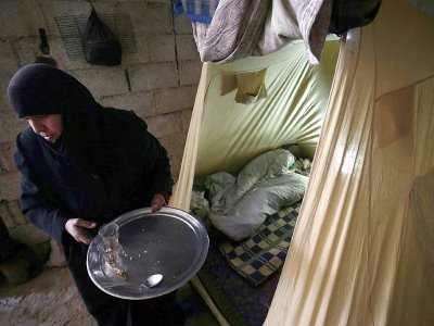Une femme syrienne, Oum Jamal, près d'une tente où dort sa fille, dans un sous-sol de la localité de Moudayra dans la Ghouta orientale bombardée par le régime syrien, le 28 janvier 2018 - ABDULMONAM EASSA [AFP/Archives]