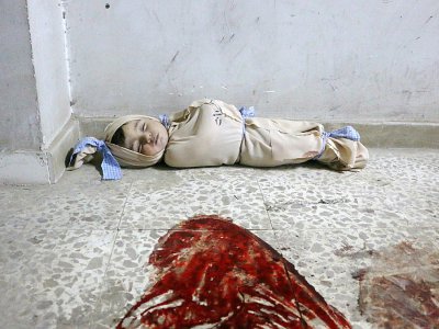 Le corps d'un enfant syrien enveloppé dans une couverture et placé à même le sol dans une clinique de fortune dans la localité de Douma, dans le fief rebelle de la Ghouta orientale, cible de bombardements intensifs du régime, le 22 février 2018 - Hamza AL-AJWEH [AFP]