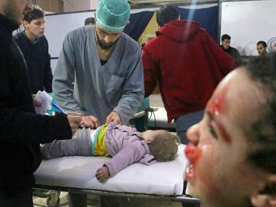 Des secouristes soignent un enfant blessé alors qu'un autre pleure dans une clinique de fortune à Douma, dans la Ghouta orientale, bombardée par le régime, le 22 février 2018 - Hamza AL-AJWEH [AFP]