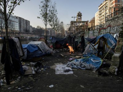 Des migrants notamment d'Afghanistan se réchauffent autour d'un feu de camp à Paris le long du Canal St Martin, le 23 février 2018 - CHRISTOPHE ARCHAMBAULT [AFP]