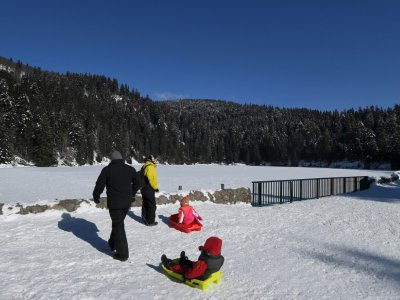 Une famille s'amuse sur le Lac vert gelé près de Soultzeren (Haut-Rhin) le 26 février 2018 - PATRICK HERTZOG [AFP]