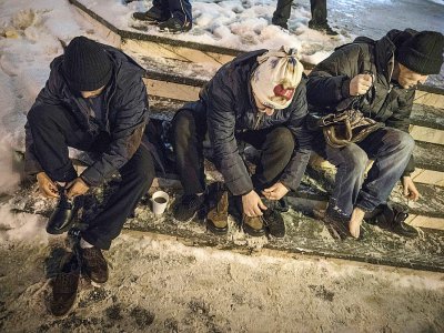 Des sans-abri enfilent des chaussures distribuées par les services sociaux à Bucarest, le 27 février 2018 - Daniel MIHAILESCU [AFP]
