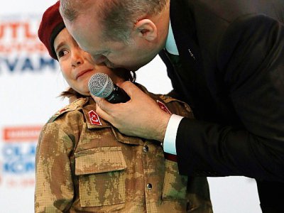 Cette photo, prise le 24 février 2018 et publiée le 28 février 2018 par le service de presse présidentiel turc, montre Recep Tayyip Erdogan embrassant Amine Tiras, une petite fille de 6 ans en treillis militaire, à Kahramanmaras - Handout [TURKISH PRESIDENTIAL PRESS SERVICE/AFP]