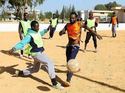 Des migrants Camerounais (orange) et Sénégalais (jaune) participent à un match de football au camp de Tarjoura en Libye, le 28 février 2018 - MAHMUD TURKIA [AFP]