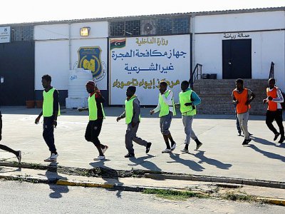 Des migrants camerounais (orange) et Sénégalais (jaune) rejoignent le terrain où ils s'apprêtent à disputer un match de football au camp de Tarjoura en Libye, le 28 février 2018 - MAHMUD TURKIA [AFP]