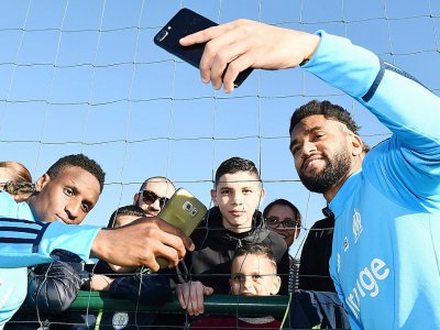 Bouna Sarr (g) et Jordan Amavi (d) prennent des selfies avec de jeunes supporters lors d'un entraînement à Robert-Louis Dreyfus, le 5 janvier 2018 - BORIS HORVAT [AFP/Archives]