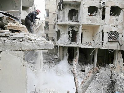 Un Syrien sur le site d'un immeuble détruit par les bombardements du régime à Hammouriyé dans la partie rebelle de la Ghouta orientale, le 22 février 2018 - ABDULMONAM EASSA [AFP]