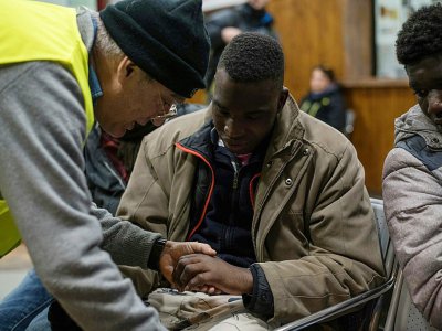 Un migrant montre à un infirmier bénévole les engelures de ses mains après sa tentative de franchir la frontière franco-italienne, le 13 janvier 2018 à Bardonecchia - Piero CRUCIATTI [AFP]