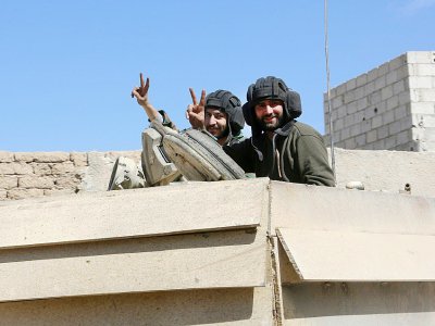 Des combattants progouvernementaux font le signe de la victoire dans la ville reconquise de Mohamadiyé, dans la Ghouta orientale, le 7 mars 2018 - STRINGER [AFP]