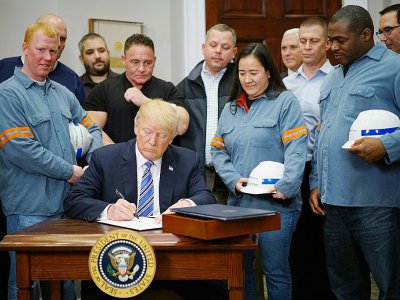 Donald Trump signant les taxes sur les importations d'acier et d'aluminium aux côtés de travailleurs du secteur à la Maison Blanche le 8 mars 2018 - MANDEL NGAN [AFP]
