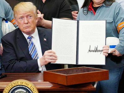 Le président américain Donald Trump montre le document qu'il vient de signer instaurant des taxes sur les importations d'acier et d'aluminium, le 8 mars 2018 à la Maison Blanche, à Washington - MANDEL NGAN [AFP]