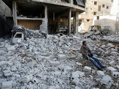 Un homme est assis au milieu des décombres dans la ville de Hammouriyé, dans la partie rebelle de la Ghouta orientale,le 9 mars  2018 - ABDULMONAM EASSA [AFP]